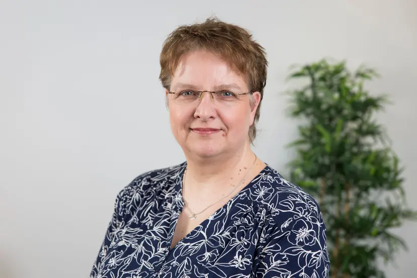 Sandra Hellbusch mit Brille und gemusterter Bluse blickt freundlich in die Kamera.