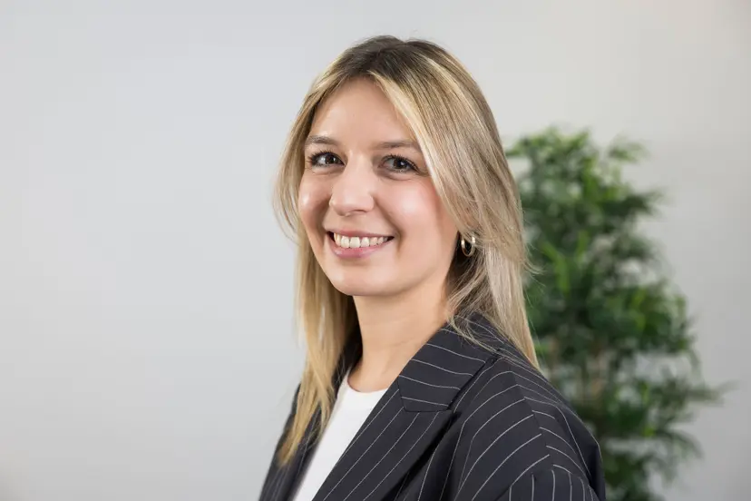 Paula Schmidt mit blondem Haar und Nadelstreifenblazer lächelt in die Kamera.